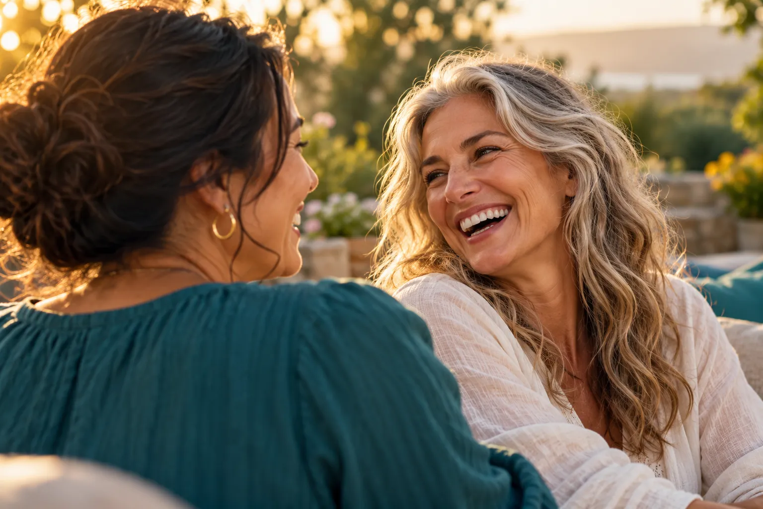Two women sharing a laugh outdoors in golden light