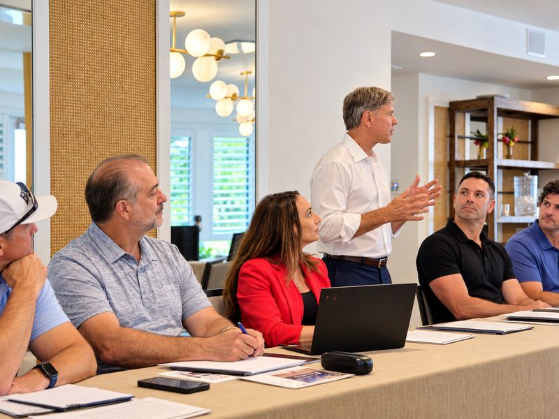An attendee standing to speak while others at the table listen