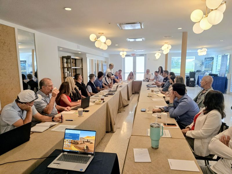 Attendees seated at long tables during a session at the BTC Elite retreat in Miami Beach